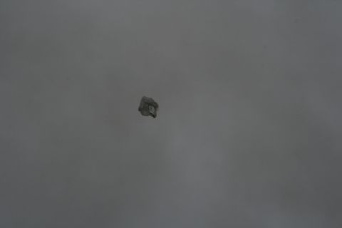 1990 Chevrolet Suburban - A close-up, slightly out-of-focus shot of a small, crumpled piece of paper or debris against a grey background.