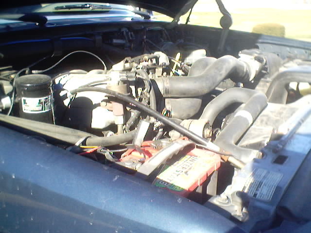 Engine bay with battery and hoses visible