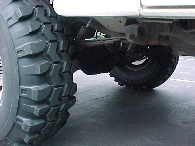 Undercarriage of lifted truck showing front axle, differential and large mud tires