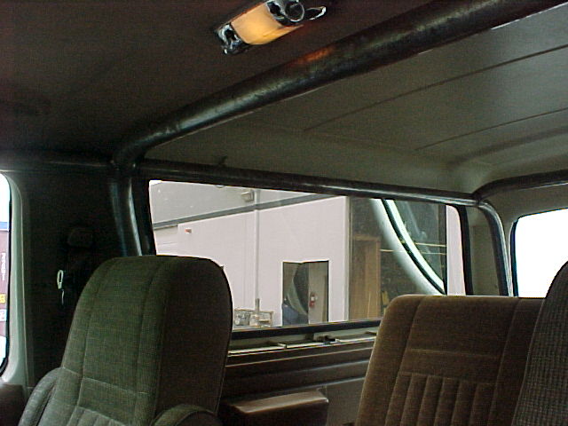 Interior of Ford Bronco showing roll cage bar across headliner behind cloth bucket seats