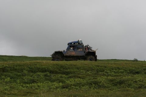 1990 Chevrolet Suburban - A modified blue off-road vehicle with large tires is parked on a grassy hill under a cloudy sky. The vehicle appears to be a custom build w…