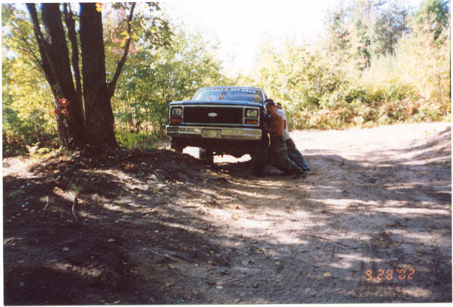 Front view of lifted Ford Bronco on dirt trail with two people beside it, dated 9/28/02