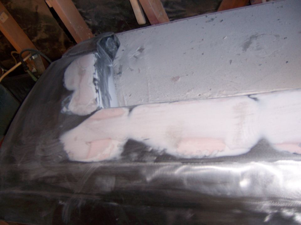 Long body panel edge with pink filler and primer in a garage