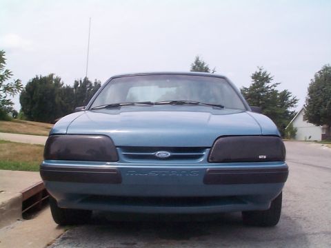 1987 Ford Mustang - This blue 1987 Ford Mustang is shown from the front, tinted headlights and the model name on the bumper.