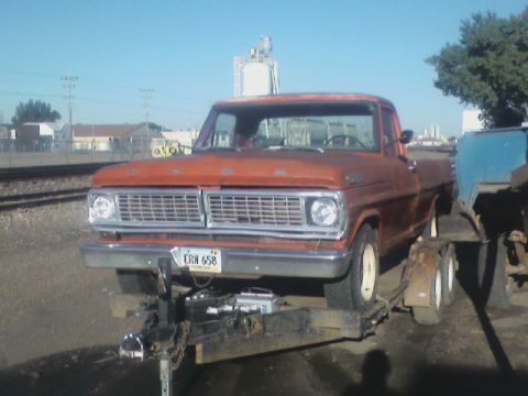 1992 Ford F-350 - This orange pickup truck, likely from the early 1970s, is seen from the front while being transported on a trailer.