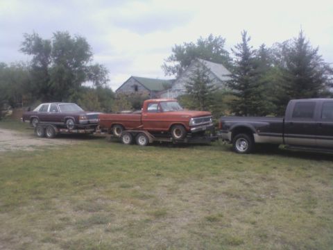 1992 Ford F-350 - Three vehicles are being towed in a convoy, with a sedan and a pickup on trailers.