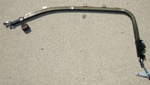 1992 Ford Probe - A detached seatbelt assembly, including the buckle and mounting components, lies on a concrete surface.