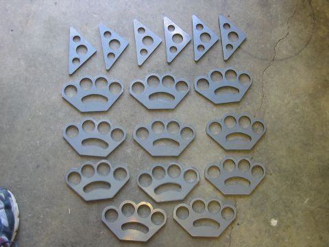 1992 Ford Mustang - Collection of metal paw print shaped parts and triangular metal pieces with multiple holes.