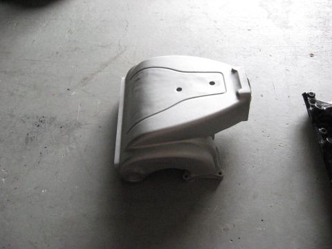 1991 Ford Bronco - A gray engine cover with two circular indentations rests on a concrete floor.