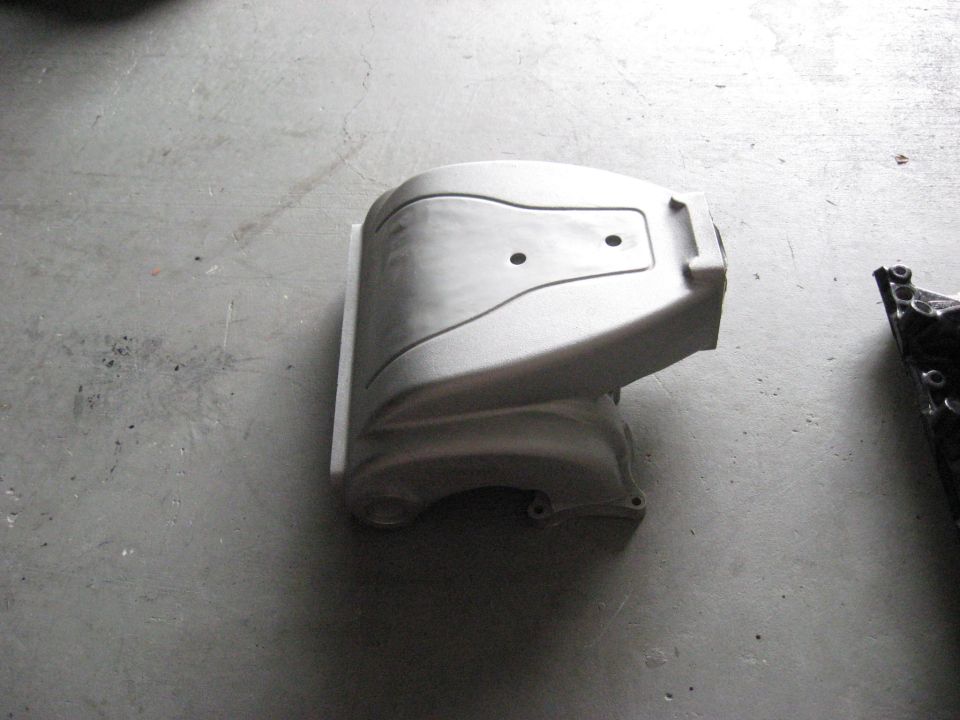 Gray engine cover with two circular indentations on a concrete floor