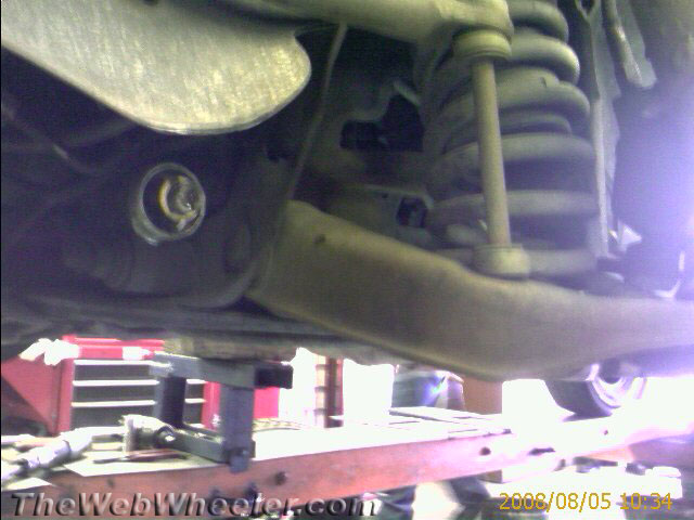 close-up of car's front suspension system with shock absorber and control arm visible