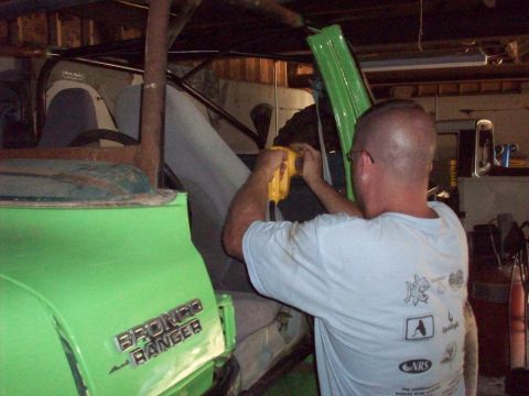 1978 Ford Bronco - A man works on the interior of a green 1978 Ford Bronco Ranger, likely during a modification or restoration project.