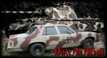 1997 Ford Crown Victoria - A sedan painted in a desert camouflage pattern is parked in front of a military tank.