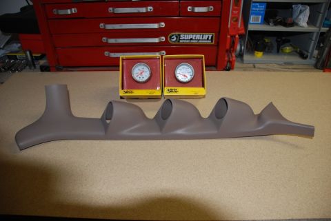1996 Ford Bronco - Photograph of a gray gauge pod and boxed Auto Meter gauges on a workbench.