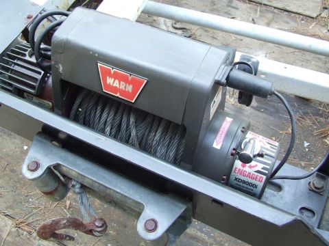 1979 Ford F-250 - A close-up view of a WARN XD9000i winch, showing its engaged lever and steel cable.