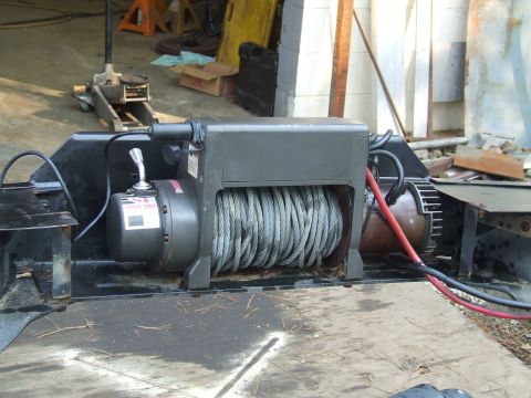 1979 Ford F-250 - A winch assembly with a coiled cable and electrical connections is shown mounted on a metal frame.