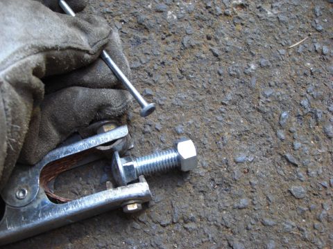 1993 Ford Bronco - A gloved hand holds a nail above a bolt secured by a welding clamp, with the Supermotors.net logo visible.