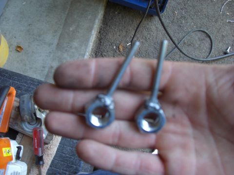 1993 Ford Bronco - Two metal eye bolts are held in a person's hand, with tools visible in the background.