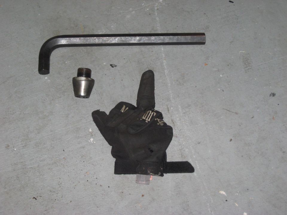 Allen wrench, threaded adapter, and black work glove on concrete floor