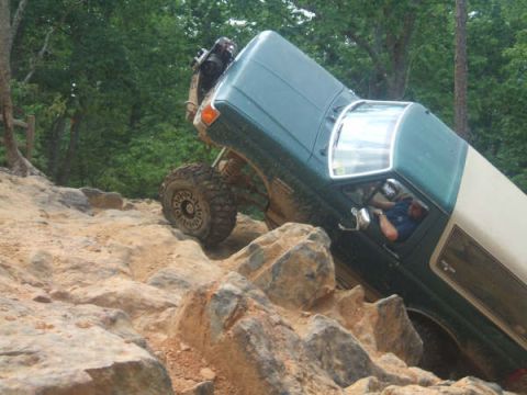1995 Ford Bronco - This SUV is navigating a difficult rocky terrain, with its tires gripping the stones.