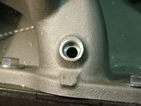 1979 Ford Bronco - A close-up view of a metal intake manifold, showing a threaded port and fasteners.