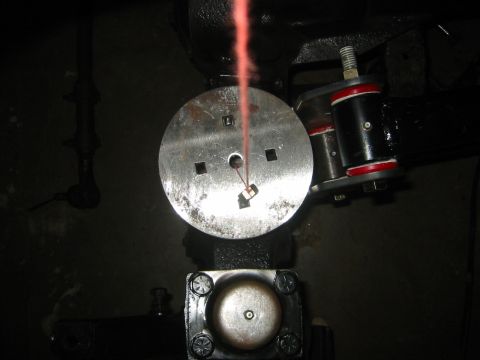 1995 Ford Bronco - A close-up view of a mechanical part with a red fluid stream, possibly part of a vehicle's suspension system.