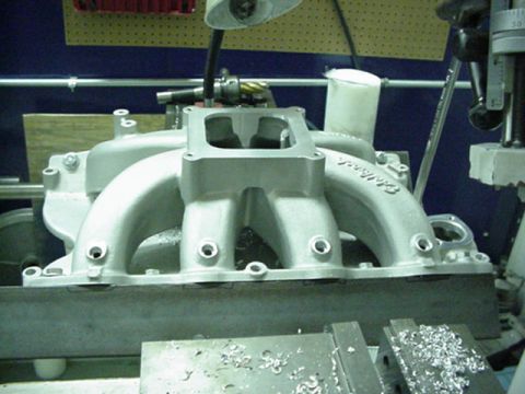 1979 Ford Bronco - Aluminum intake manifold with Edelbrock branding sits on a workbench with metal shavings.