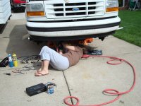 1996 Ford Bronco - A person works on the underside of a white Ford truck, with the front grille and bumper clearly visible.