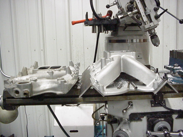 Two aluminum intake manifolds on a milling machine, one being worked on