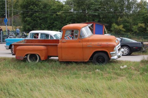 1978 Ford Bronco - An orange 1955 GMC pickup truck is parked next to other vehicles.