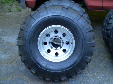 1979 Ford Bronco - Close-up of a red vehicle's large off-road tires and silver rims.