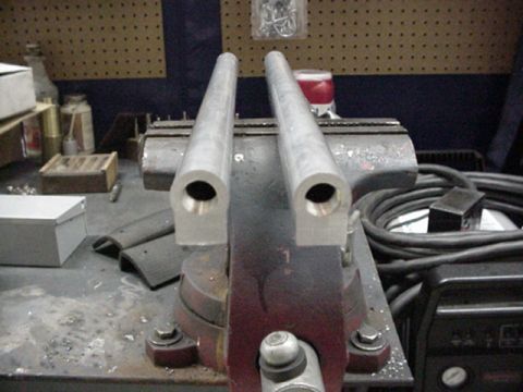 1979 Ford Bronco - Two aluminum tubes are clamped in a vise on a workbench, with various tools and parts in the background.