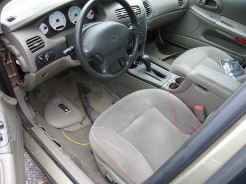 2001 Ford Crown Victoria - The interior of a car shows the dashboard, steering wheel, and front seats with some damage to the trim.