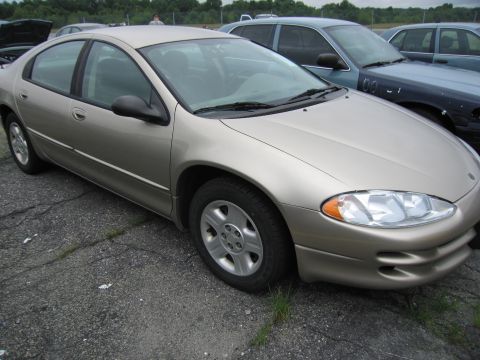 2001 Ford Crown Victoria - A gold sedan is parked on cracked asphalt with other vehicles in the background.