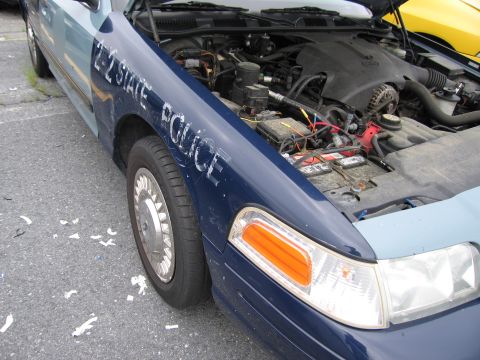 2001 Ford Crown Victoria - Front view of a 2001 Ford Crown Victoria police car, showing the fender with text and the open engine compartment.