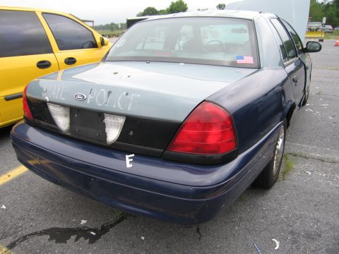 2001 Ford Crown Victoria - Rear view of a 2001 Ford Crown Victoria police car, showing 'STATE POLICE' text and an American flag sticker.