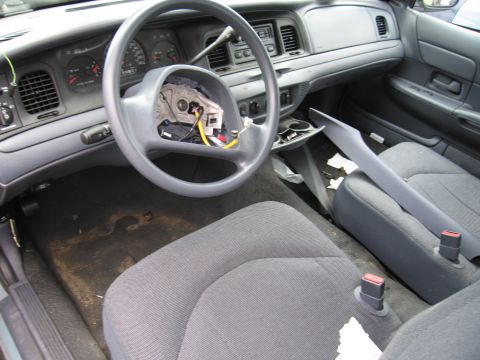 2001 Ford Crown Victoria - The interior of a 2001 Ford Crown Victoria shows a disassembled steering wheel and worn seats.