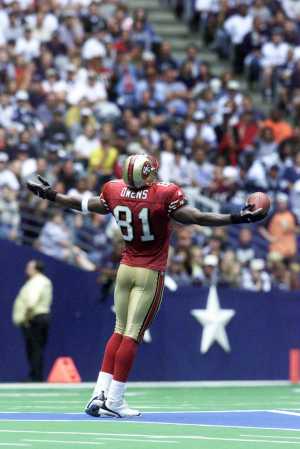 1988 Ford Bronco - A football player in a red uniform, identified by the number 81 on his jersey, stands on the field with his arms extended.