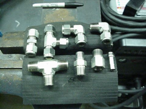 1979 Ford Bronco - Various metal plumbing fittings are laid out on a textured surface, with a Sharpie marker visible above.
