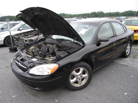 2001 Ford Crown Victoria - Black sedan in a lot, hood open to reveal the engine bay. Another vehicle is visible behind it.