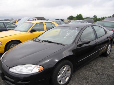 2001 Ford Crown Victoria - A black sedan is parked in a lot with other vehicles, including a yellow car.
