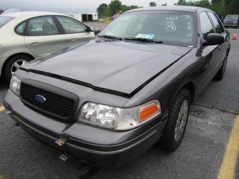 2001 Ford Crown Victoria - A dark gray 2001 Ford Crown Victoria is parked outdoors with its hood open, showing handwritten markings on the windshield.