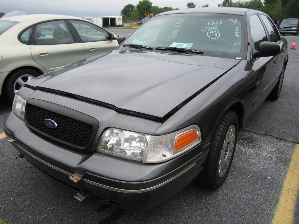 Dark gray 2001 Ford Crown Victoria, front view, hood ajar, with handwritten numbers on windshield