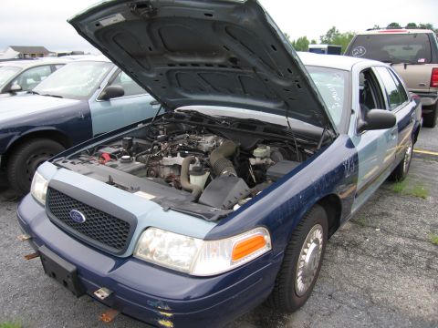 2001 Ford Crown Victoria - The front 3/4 view of a 2001 Ford Crown Victoria shows its engine with the hood open, parked next to another vehicle.