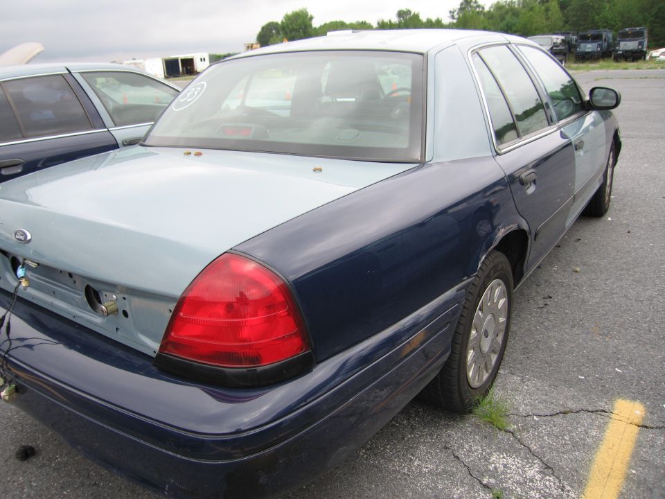 Rear of a blue and light blue Ford Crown Victoria, parked next to another similar car