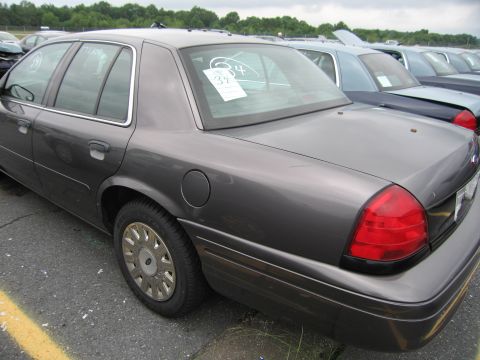 2001 Ford Crown Victoria - A dark gray 2001 Ford Crown Victoria is parked in a lot with other vehicles, viewed from the rear quarter.