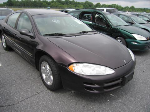 2001 Ford Crown Victoria - A dark purple sedan is parked in a lot with other vehicles under an overcast sky.