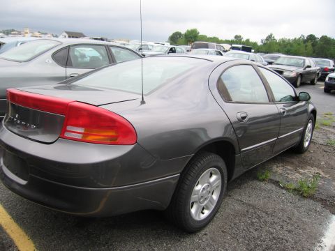 2001 Ford Crown Victoria - A dark gray sedan is parked in a lot with other vehicles under a cloudy sky.