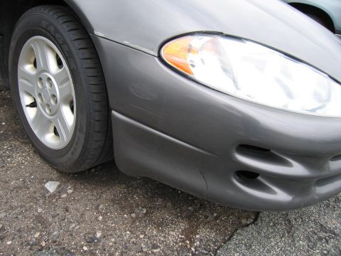 2001 Ford Crown Victoria - Close-up of the front passenger side of a gray Dodge Intrepid, highlighting the headlight and wheel.