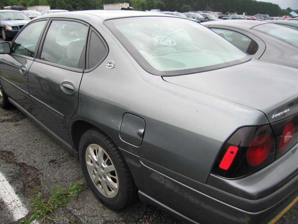 Gray sedan, rear quarter panel view, showing a dented fuel door and aftermarket tinted taillights